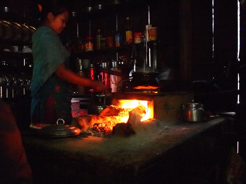 Child cooking over open-fire stove inside a home