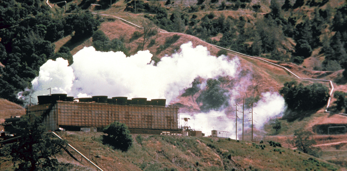 Uma fotografia mostra uma usina de energia em uma encosta com nuvens de vapor branco imediatamente acima da usina