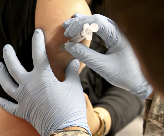 La photo montre une personne recevant une injection dans le bras.