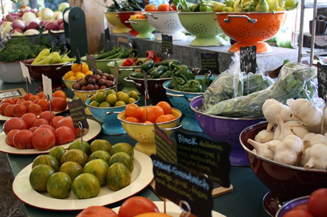 Photo shows a variety of fresh vegetables being sold at a market.