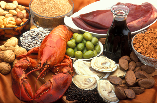 تظهر الصورة مجموعة متنوعة من الأطعمة، بما في ذلك سرطان البحر والمحار والمكسرات والكبد.