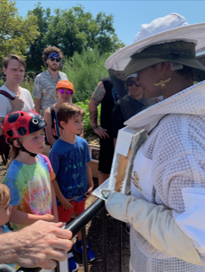 Stacey Vázquez haciendo educación de abejas frente a grupo juvenil afuera