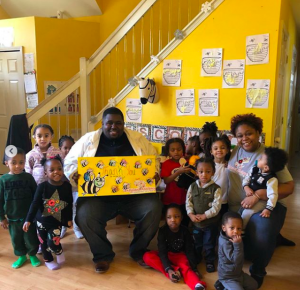 Timothy Jackson sostiene papel de arte de abeja con un grupo joven de niños