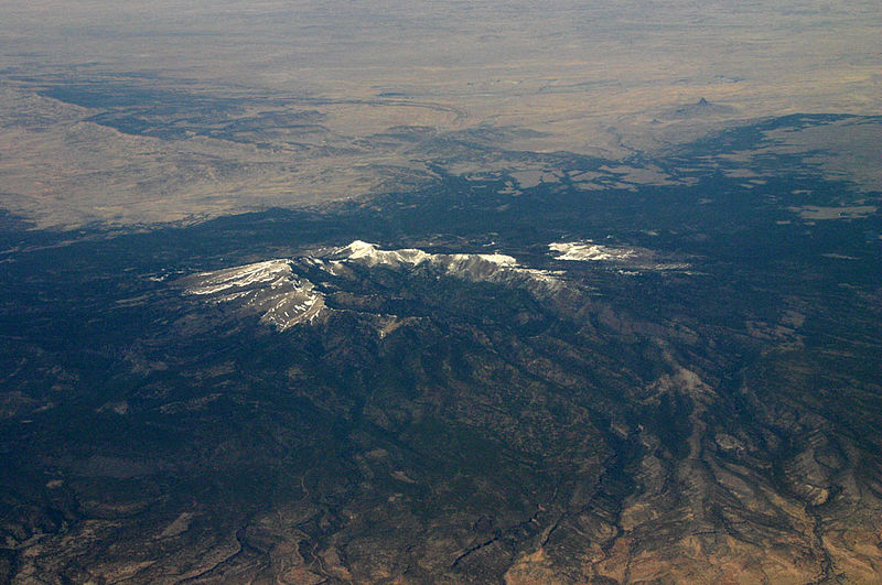 Aerial view of the Santa Teresa Mountains. There is snow at the top of the mountains, but the surrounding region is lower elevation.