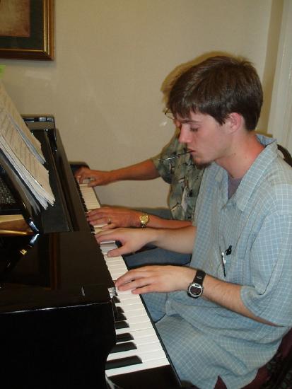 two individuals playing one piano