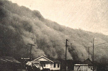 A wall of dust approaches a Kansas town, as shown in this black and white photo.