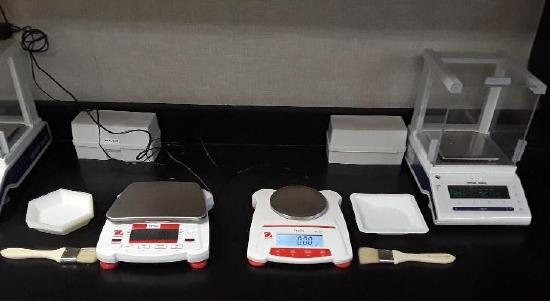 photo of digital balances in 3 varieties with weigh boats and paintbrushes near the balances