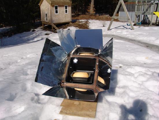 Bread bakes in a solar oven in the snow. Reflective mirrors focus sunlight inside.