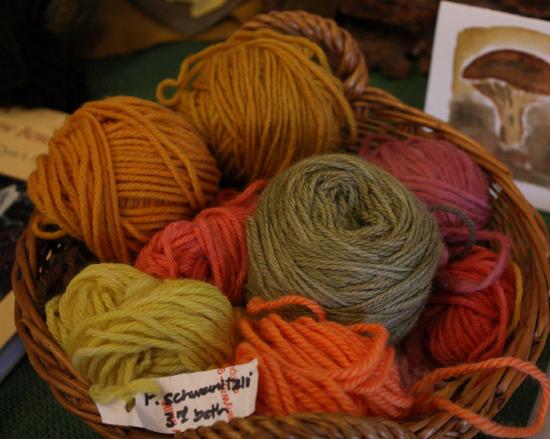 A basket of different colored yarn. there are a variety of colors, including yellow, green, orange, pink, and brown.
