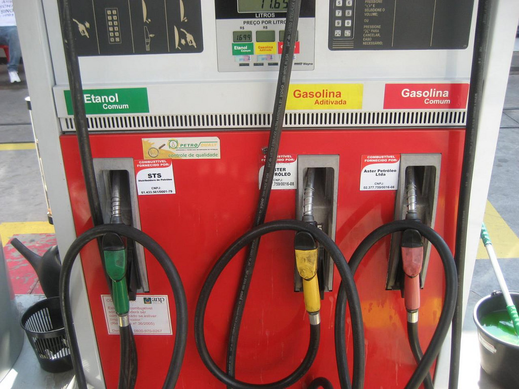 A photograph of a gasoline and ethanol pump with three separate nozzles: one for ethanol, one for premium gasoline, and one for regular gasoline.