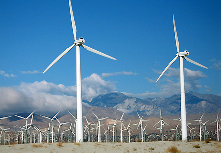 Tall, white wind turbines, each with three blades on a desert landscape
