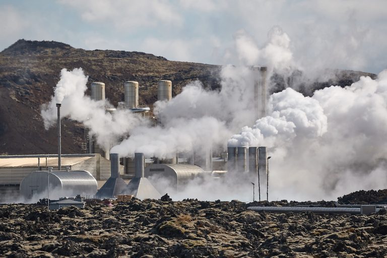 Steam emerges from a geothermal power plant, a network of metal structures