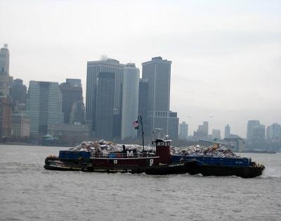 Um navio cheio de lixo no mar com uma paisagem urbana ao fundo