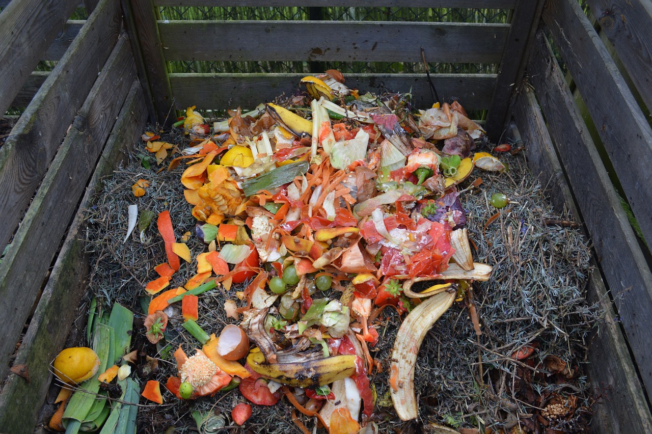 A wood container with food waste and dead grass in it.