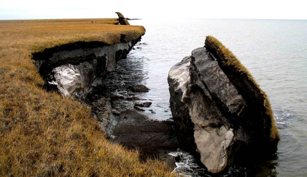 A photograph shows a huge chunk of the coastal permafrost breaking off from the rest and falling into the ocean.