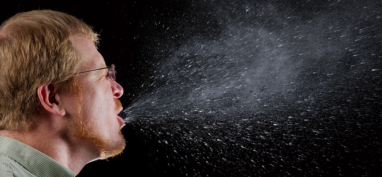 Persona estornudando; se muestra el spray para estornudar.