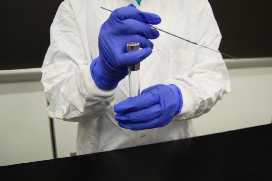 Photograph showing how to remove the cap of a culture tube using the little finger of your loop hand.