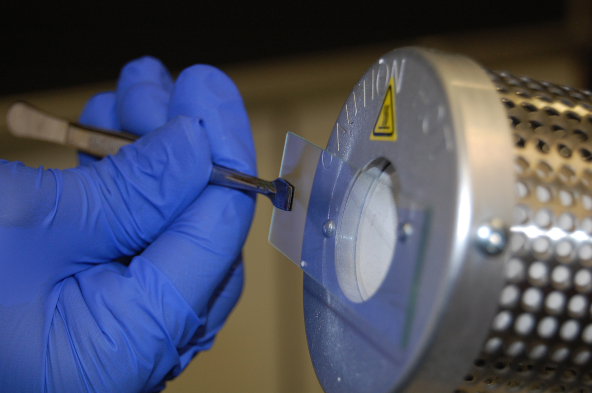 Photograph showing how to use a microincinerator to heat fix a bacterial smear on a slide.