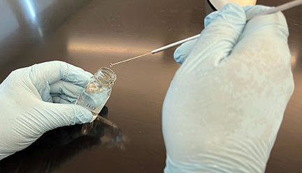 Photograph showing how to remove a loopfull of deionized water from a dropper bottle.