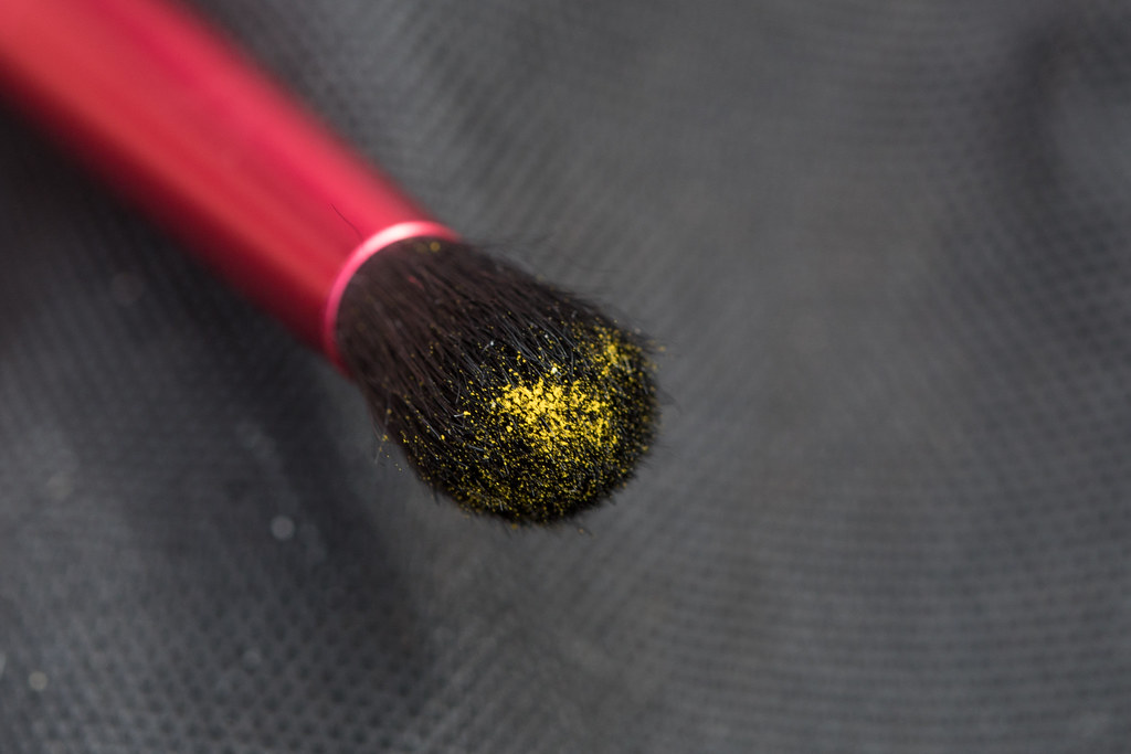 close up view of a paint brush with yellow pollen on the bristles.