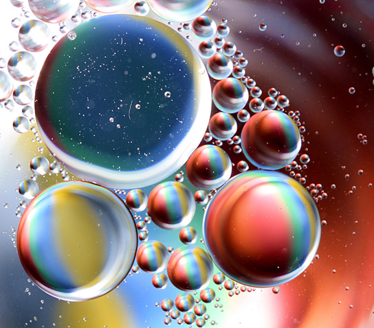 A close-up of round oil droplets floating on water.